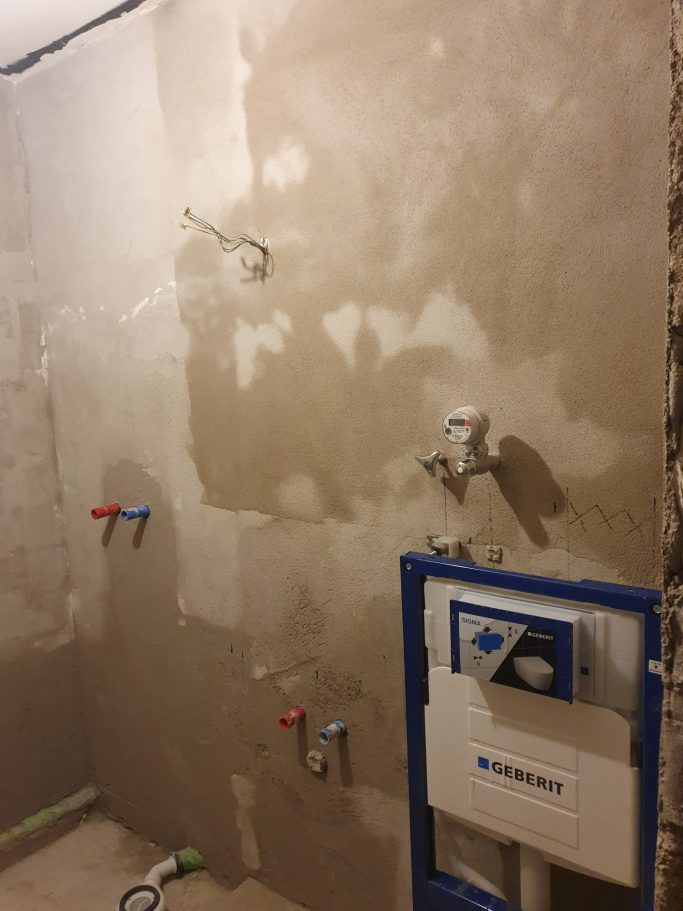 Badrenovierung Wand mit Putz und Wasseranschlüssen für Sanitärinstallation.