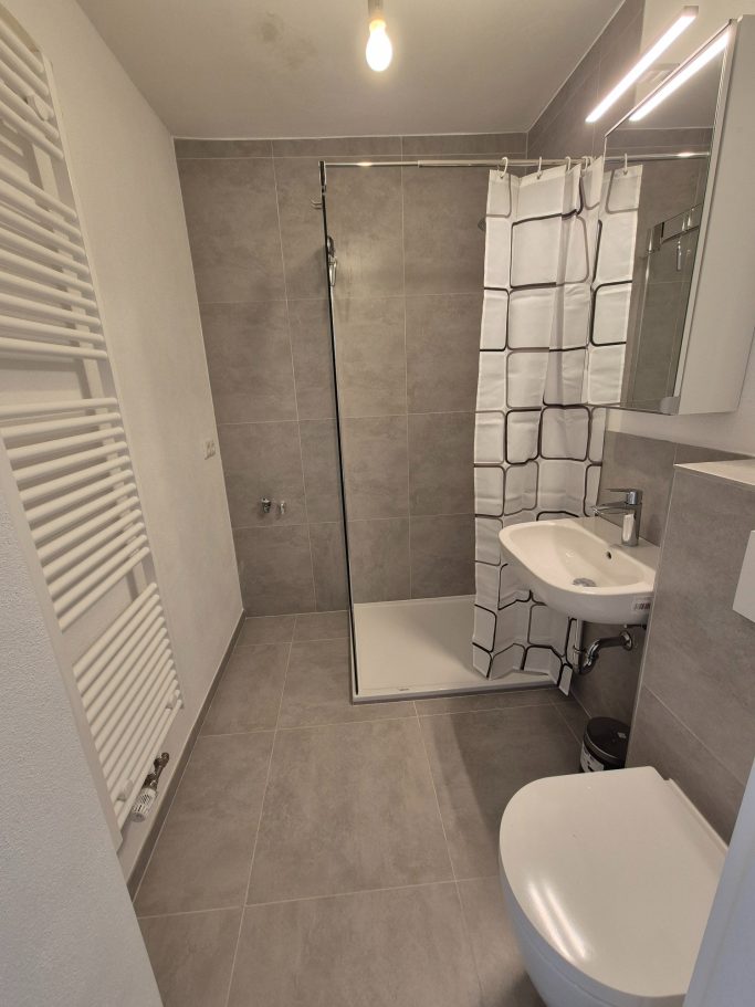 Moderne Badezimmeransicht mit Dusche, Waschbecken und WC in neutralen Farben.