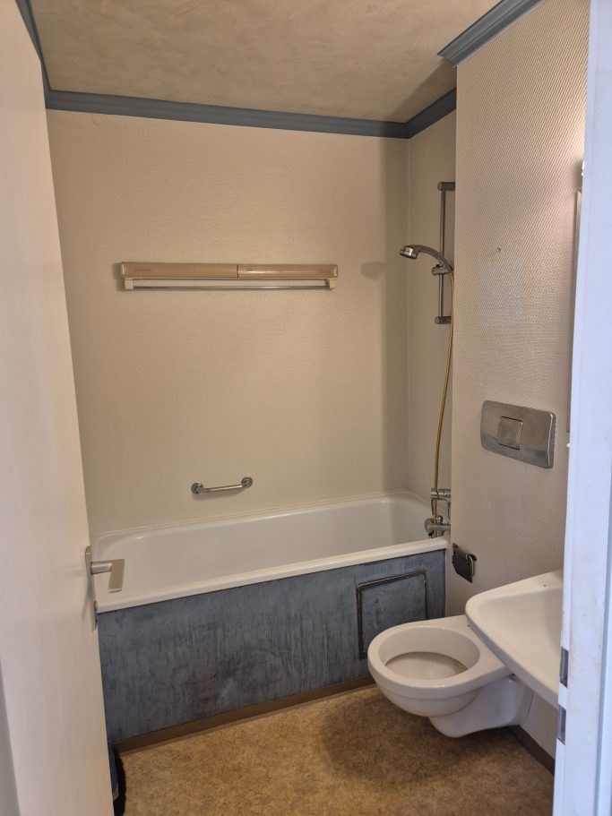 Badrenovierung Badezimmer mit Badewanne, Dusche und Toilette, helle Wände und Bodenbelag.