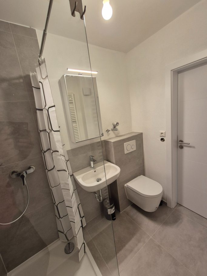 Modernes Badezimmer mit Dusche, Waschbecken und WC in neutralen Farben.