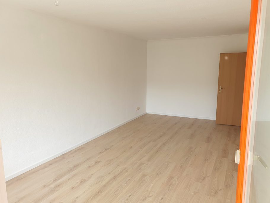 Leerer Raum mit hellen Wänden und einem Holzfußboden.